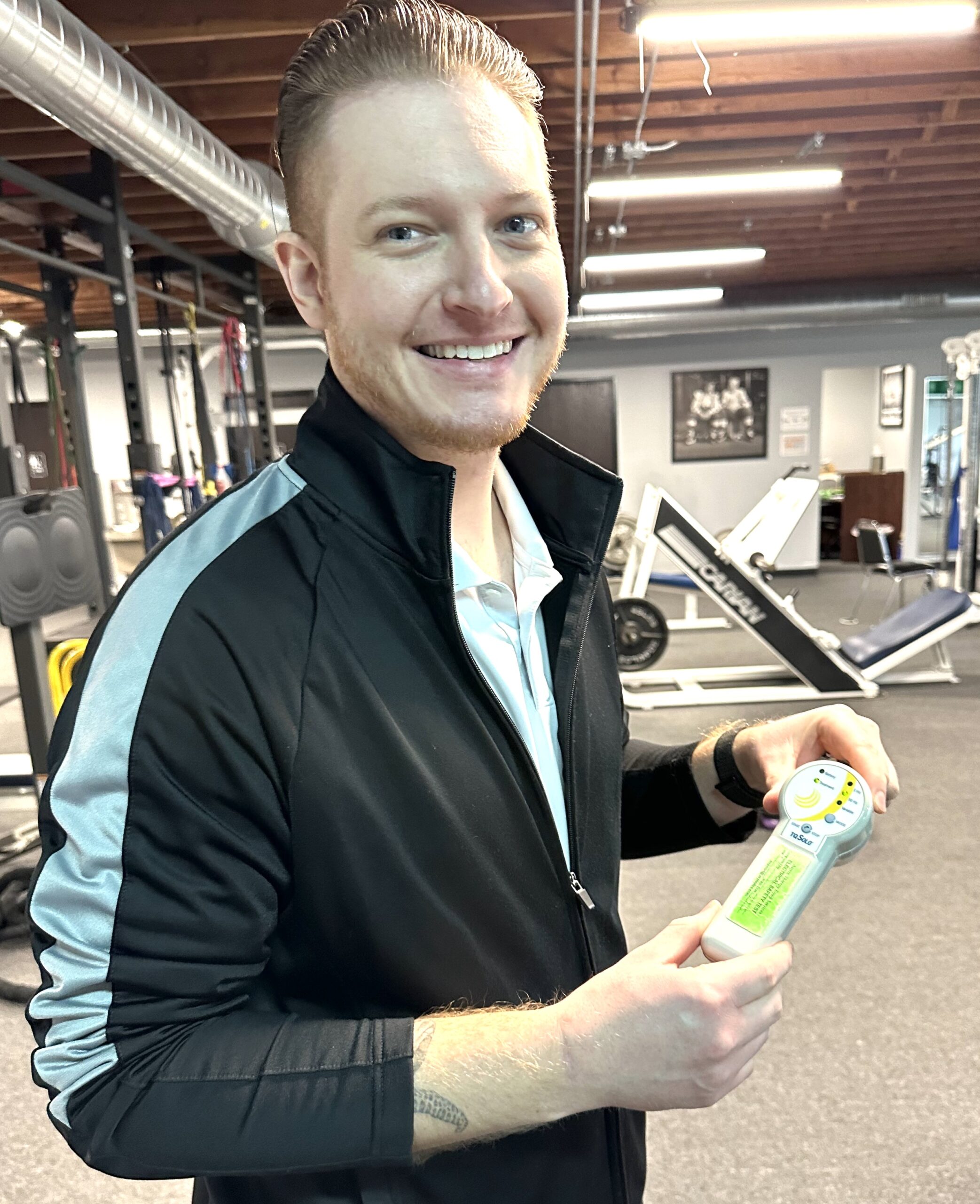 Assistant Physical Therapist Doug Ross holds a device that treats tendon injuries with a laser.
