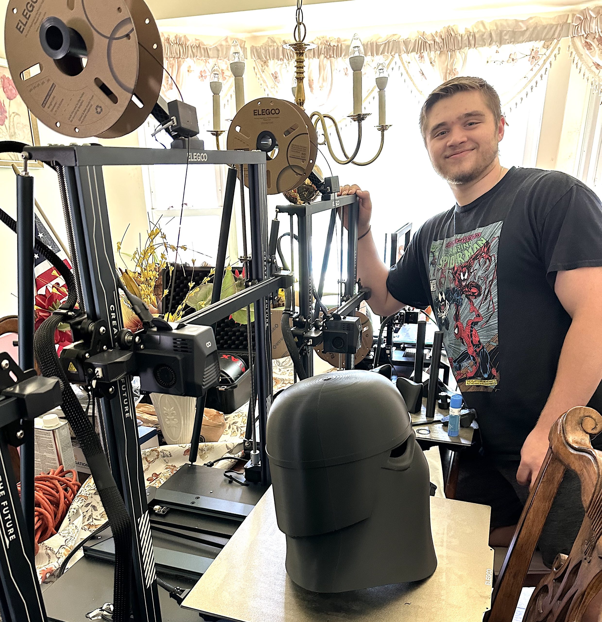 Jonah Radwanski stands next to his 3D printers that sit on the family dining room table