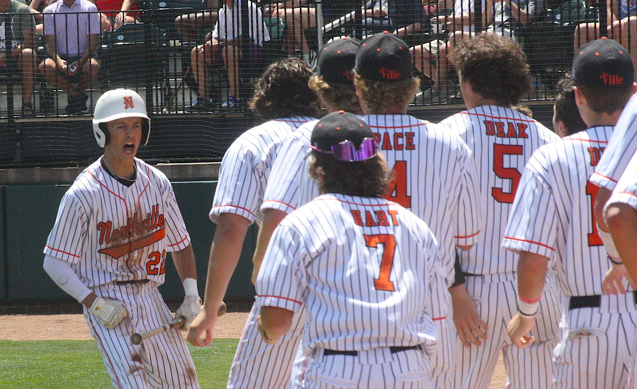 Carson Eaton is greeted by jubilant teammate after scoring the first run of the game.