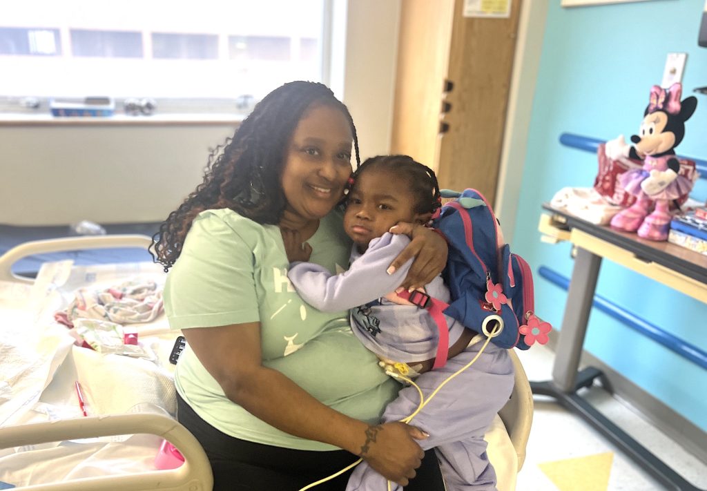 A patient at Children's Hospital of Michigan is held by her mother after receiving Christmas gifts through the hospital's Snowpile project.