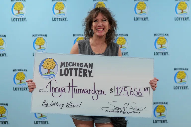 Tonya Hunwardsen holds an oversized check presented at Lottery headquarters in Lansing.