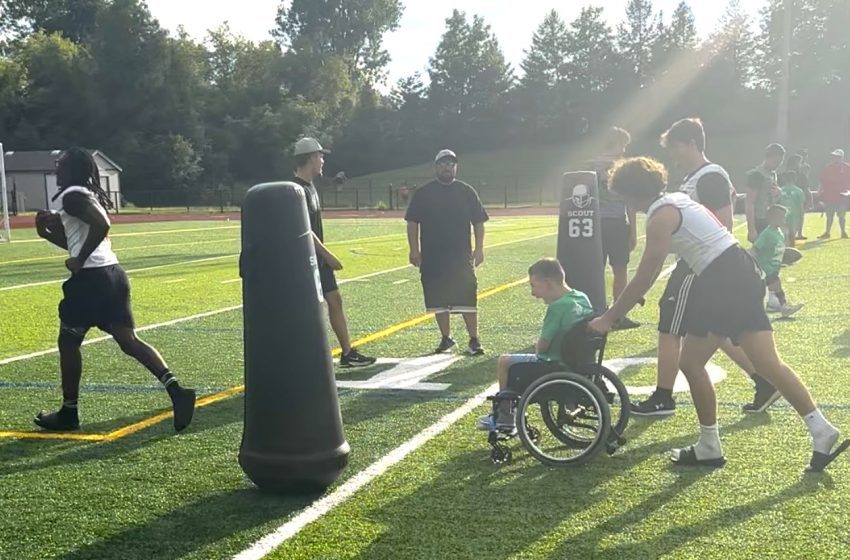 A clinic attendee smiles broadly as he is pushed into the end zone by a Churchill football player.