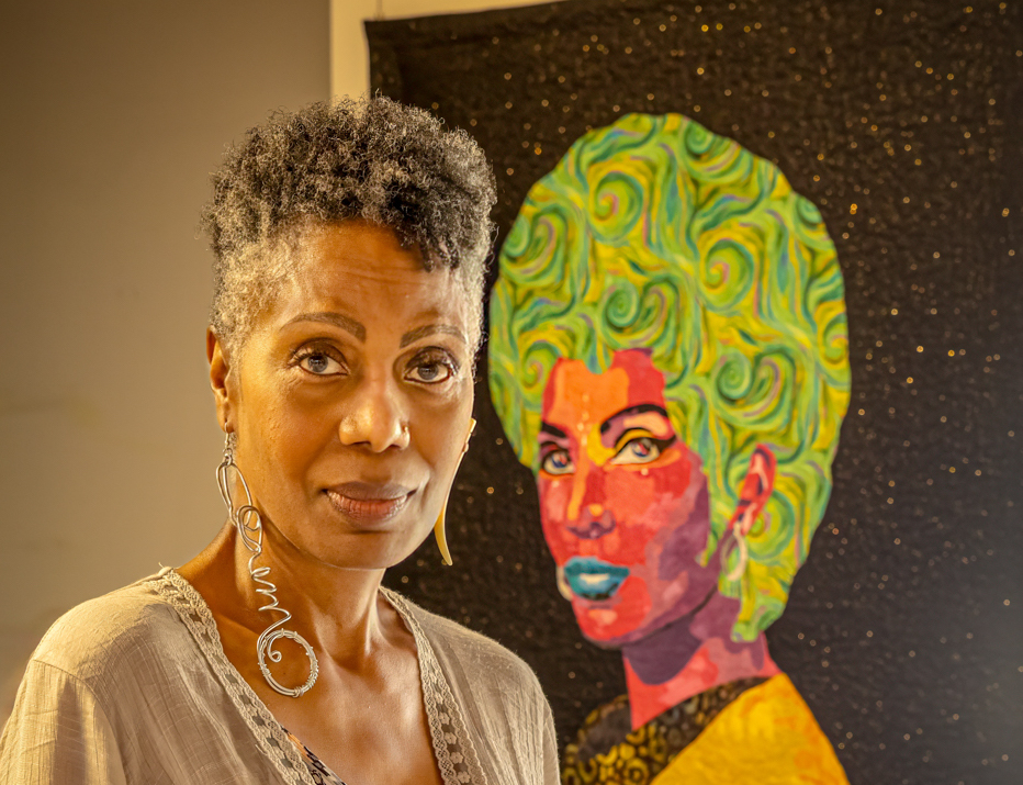 An artist stands beside her painting at the 2024 Emerge! art festival.