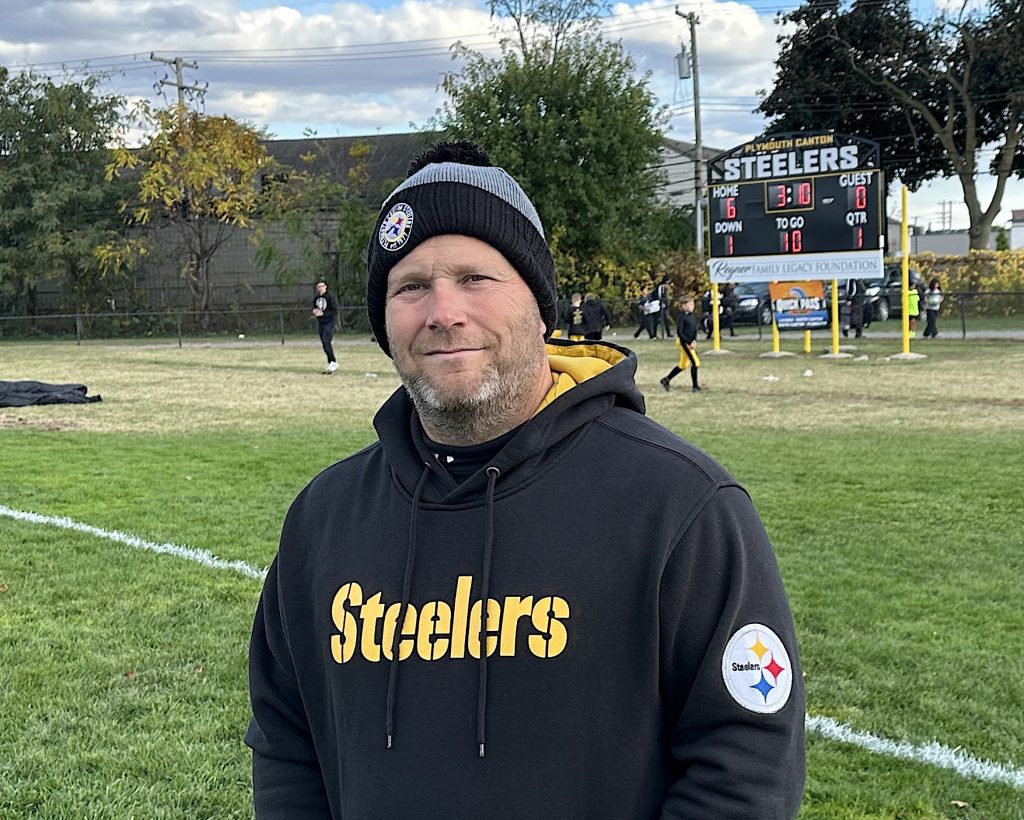 Plymouth-Canton Steelers Football Unit Director Mike Brannan stands in front of the organization's new $12,000 scoreboard.