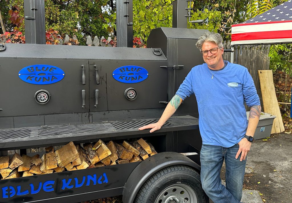 Randall Kuna stands next to his new smoker that sits behind Blue Kuna Smokehouse, which opens Saturday at 11 a.m. at 600 W. Ann Arbor Trail in Plymouth.
