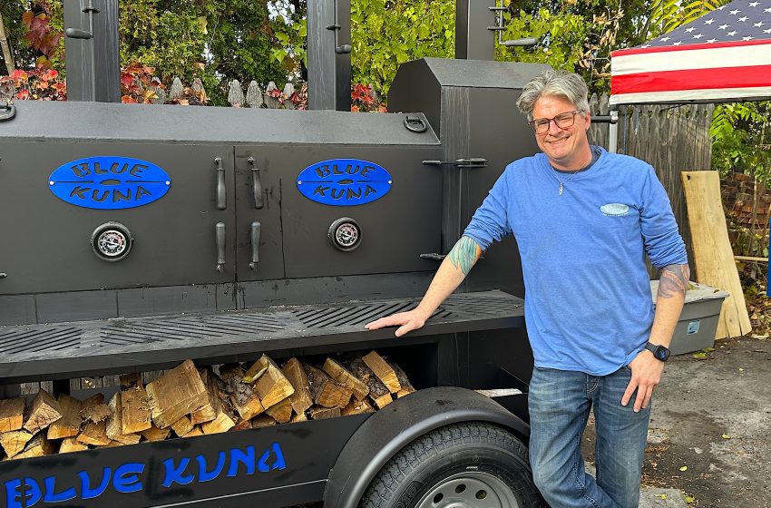 Randall Kuna stands next to his new smoker that sits behind Blue Kuna Smokehouse, which opens Saturday at 11 a.m. at 600 W. Ann Arbor Trail in Plymouth.