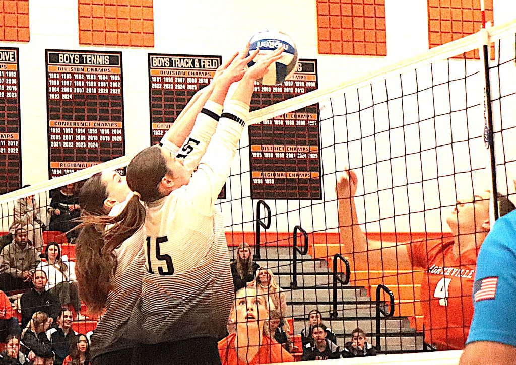 South Lyon East's Brooke Scheuher (15) combines with a teammate for a successful double block against Northville.