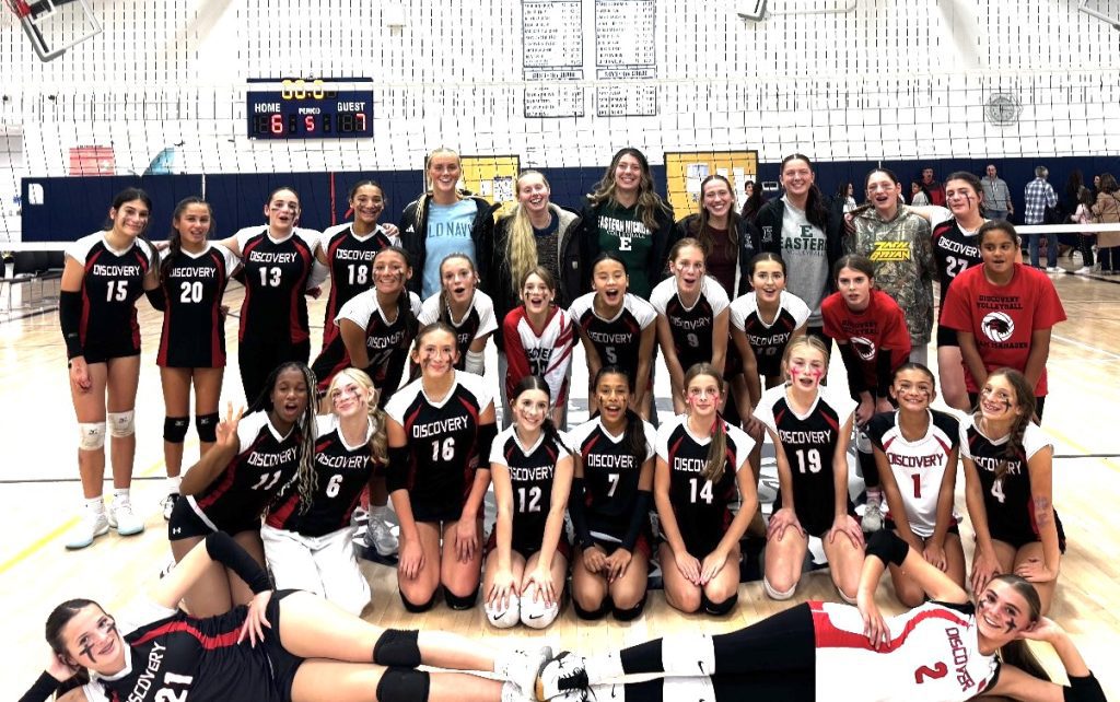Five members of the Eastern Michigan University volleyball team are pictured with Discovery Middle School volleyball players after the Eagles players watch Discovery take on Liberty Middle School.