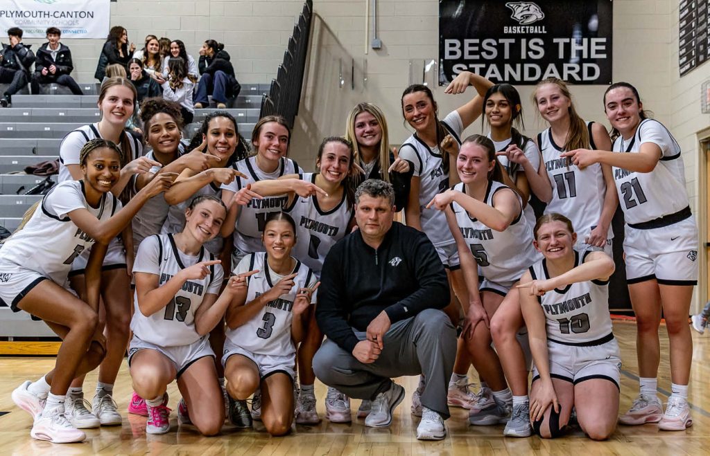 Plymouth girls basketball coach Ryan Ballard is pictured with his team after setting the school's record for basketball victories with 123. PHOTO BY VASILNEK IMAGES