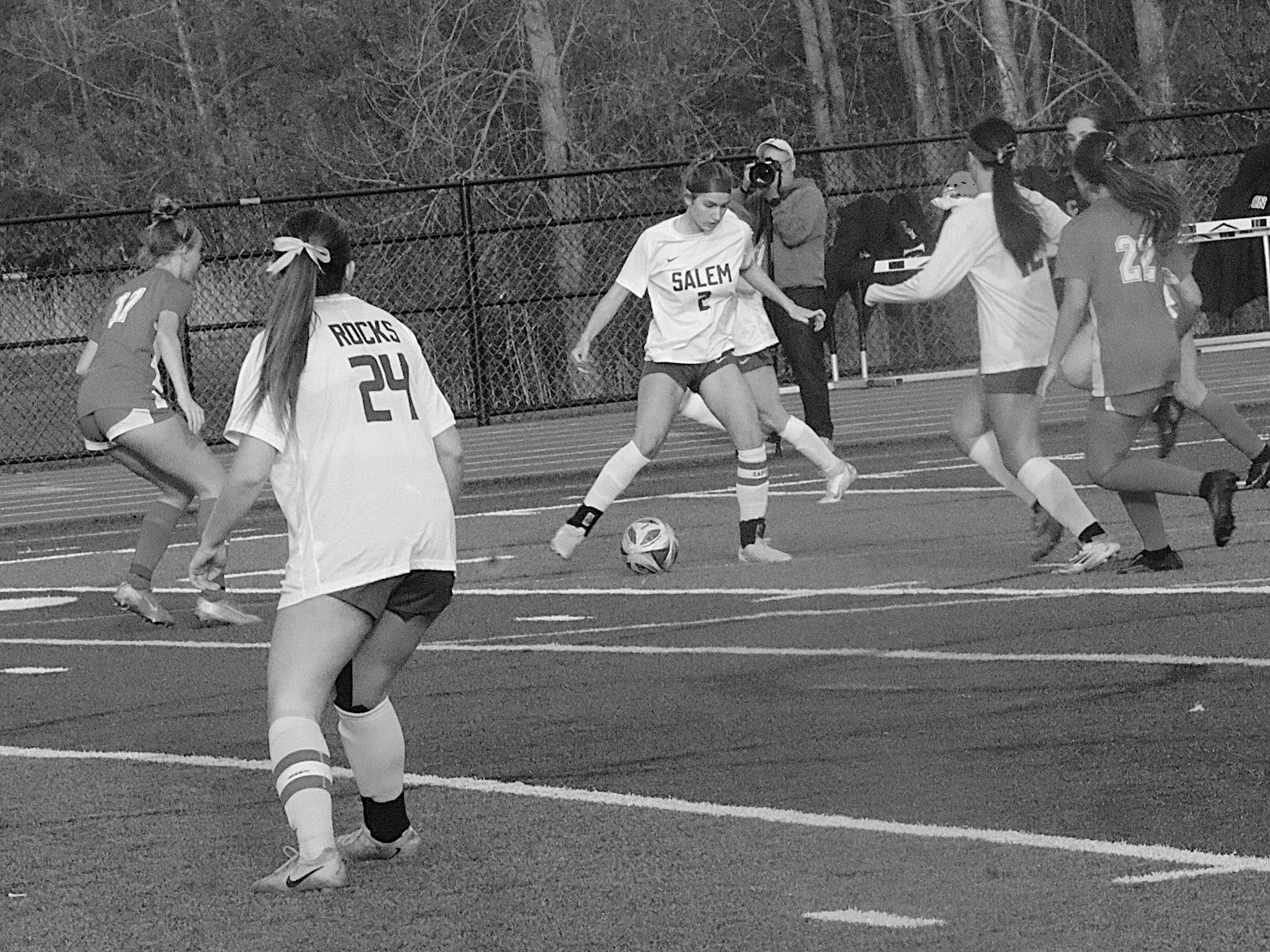 Girls soccer game on an outdoor track, Salem player (no. 2) dribbling the ball while teammates defend nearby.