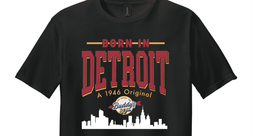 Black T-shirt with a retro Detroit graphic: bold 'BORN IN DETROIT' text, skyline silhouette, and Buddies 80th emblem in red, gold, and white colors.