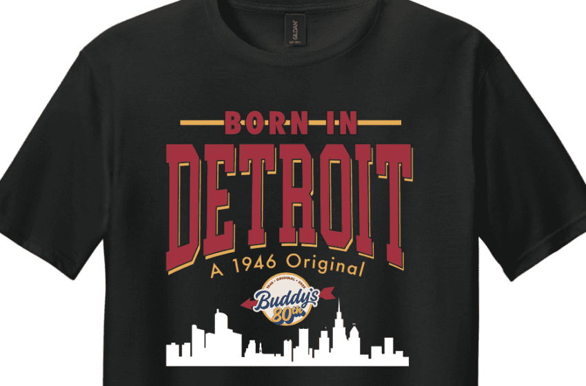 Black T-shirt with a retro Detroit graphic: bold 'BORN IN DETROIT' text, skyline silhouette, and Buddies 80th emblem in red, gold, and white colors.