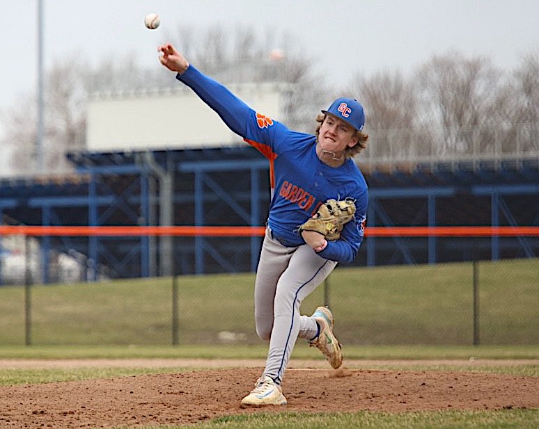 Baseball pitcher in a blue uniform throwing a pitch from the mound, glove on his left hand.