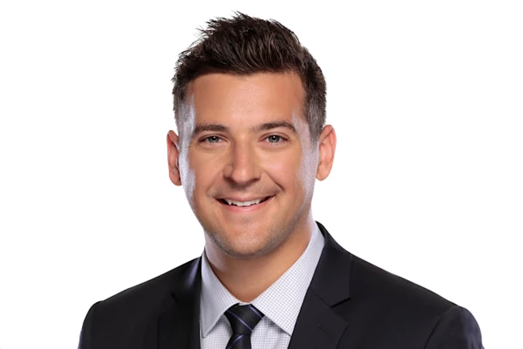 Smiling man in a dark suit and striped tie; head-and-shoulders portrait against a white background.
