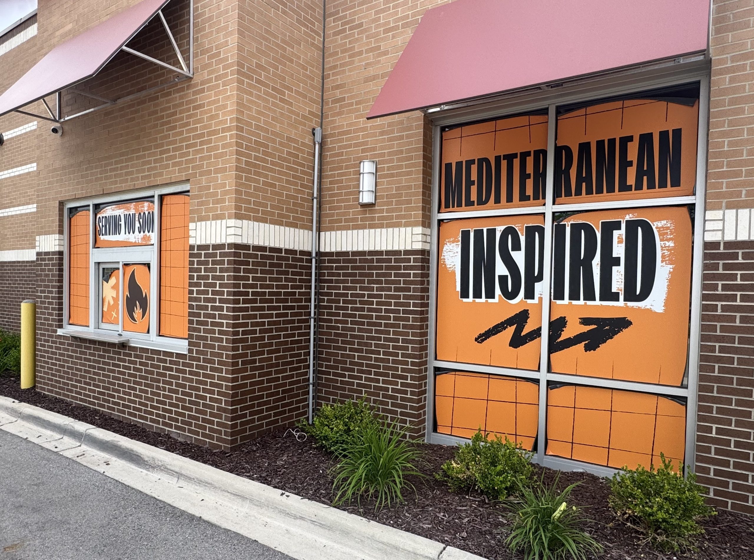 eats2 - Social House News Exterior of a Mediterranean restaurant storefront with orange windows and a 'SERVING YOU SOON' sign visible on the left panel.